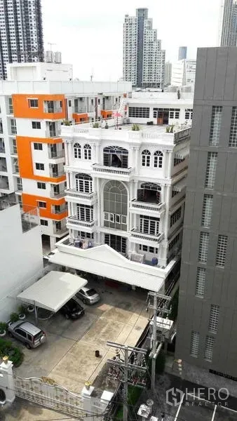 สำนักงาน ให้เช่าในKhlong San, Bangkok - มุมสูงของอาคารสำนักงานเดี่ยวสีขาว ท่ามกลางตึกเมือง พร้อมที่จอดรถและทิวทัศน์สกายไลน์กรุงเทพฯ