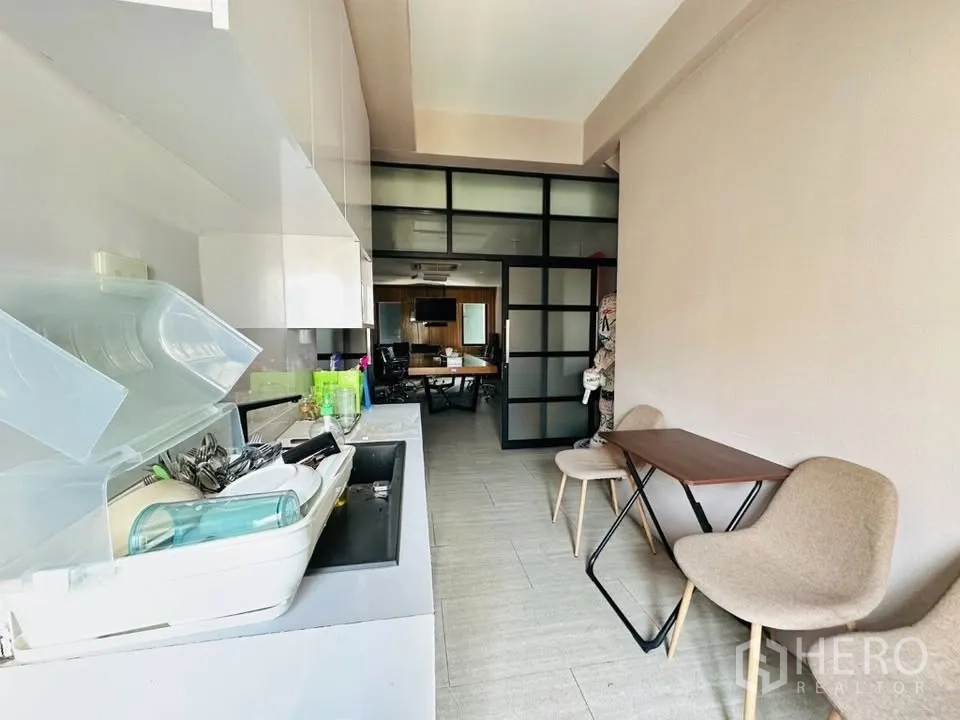 店屋 for sale in Watthana, Bangkok - 紧凑茶水间与水槽，通向玻璃隔断的办公室或会议室。