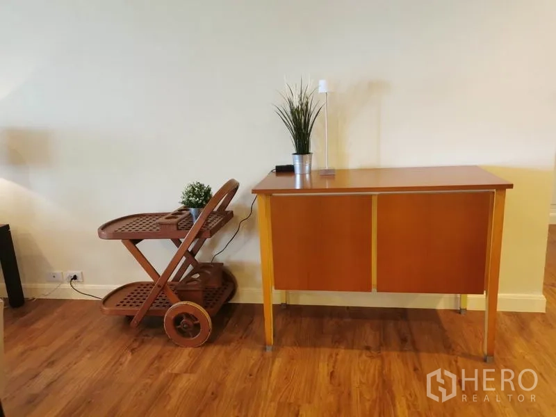 Condominium for rent in Watthana, Bangkok - Corner with wooden serving trolley and compact console on wood flooring.