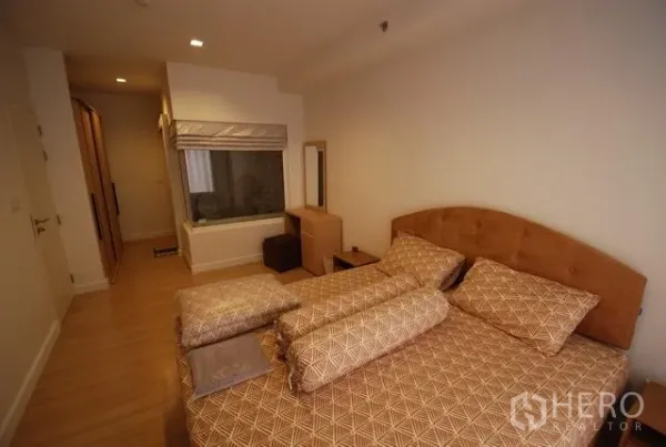 公寓 出租在Sathon, Bangkok - 卧室视角，可见衣柜与通向浴室的玻璃隔断及梳妆台。