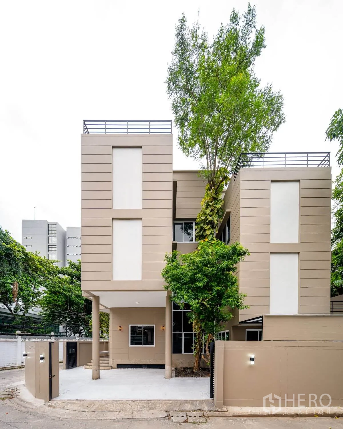 Detached House for rent or sale in Chatuchak, Bangkok - Modern three-story detached house exterior with driveway, trees, and perimeter wall.