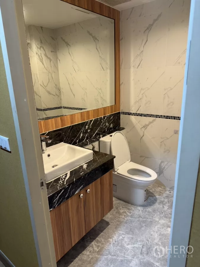 Shophouse for rent - Modern bathroom with marble-look tiles, large mirror, wood vanity, and black stone countertop.