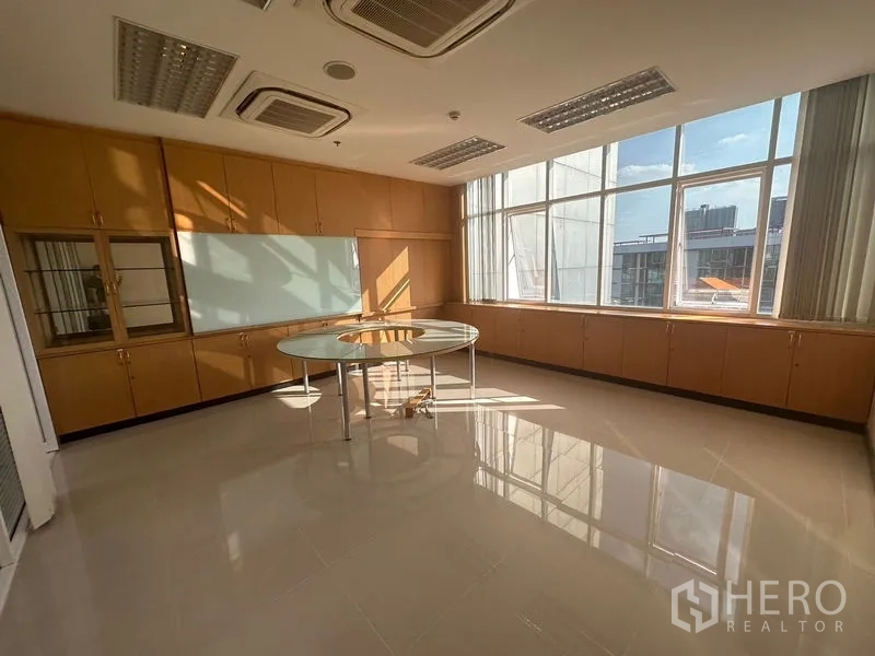 Office Space for rent in Suan Luang, Bangkok - Private executive room with corner windows, built-in cabinetry, and a round glass meeting table.