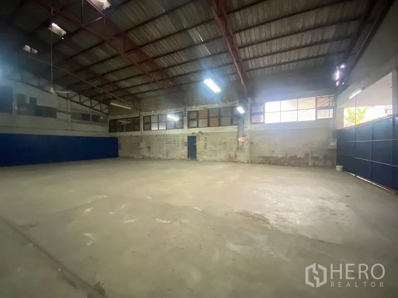 Warehouse for rent or sale in Suan Luang, Bangkok - Corner angle of the warehouse showing clerestory windows, glass partitions and expansive open space.