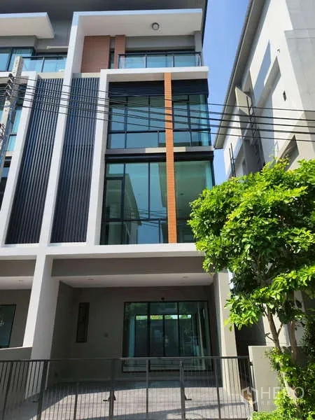 Home Office for rent in Bueng Kum, Bangkok - Modern multi-level home office exterior with large glass windows, vertical fins, and a gated covered carport in Bueng Kum.
