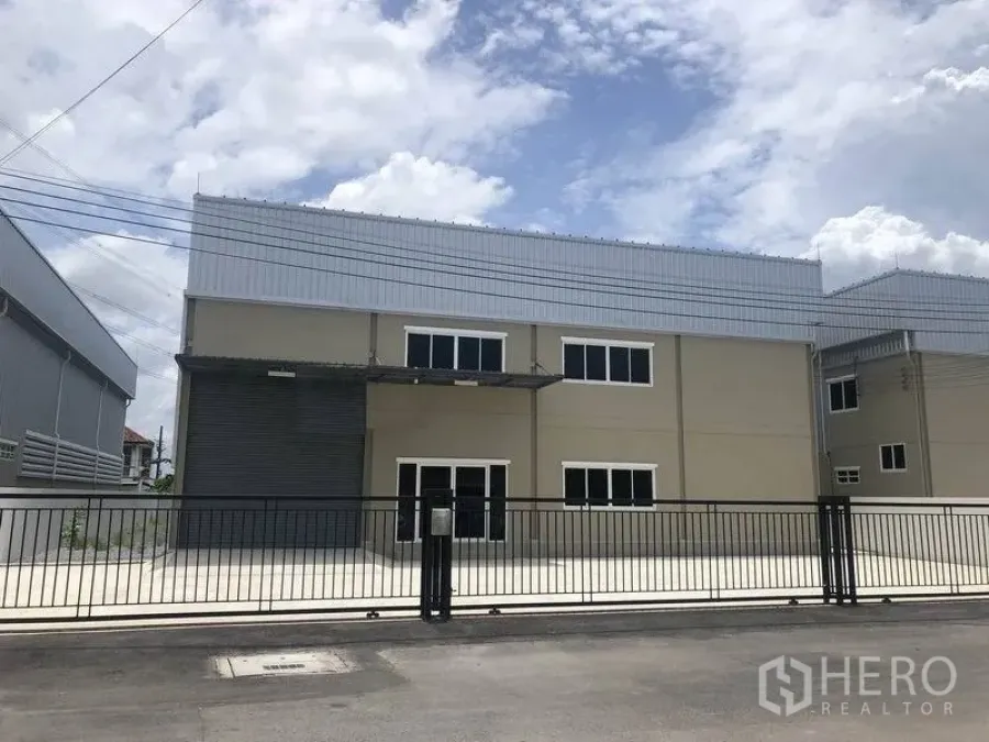 คลังสินค้า ให้เช่าหรือขายในBang Phli, Samut Prakan - โกดังสองชั้นสไตล์โมเดิร์น หลังคาเมทัลชีท ประตูม้วนโหลดสินค้า หน้าต่างออฟฟิศ และลานคอนกรีตพร้อมรั้วหน้าบ้าน ในบางพลี.