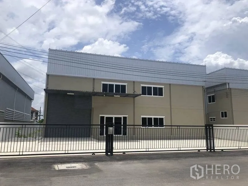 คลังสินค้า ให้เช่าหรือขายในBang Phli, Samut Prakan - โกดังสองชั้นสไตล์โมเดิร์น หลังคาเมทัลชีท ประตูม้วนโหลดสินค้า หน้าต่างออฟฟิศ และลานคอนกรีตพร้อมรั้วหน้าบ้าน ในบางพลี.