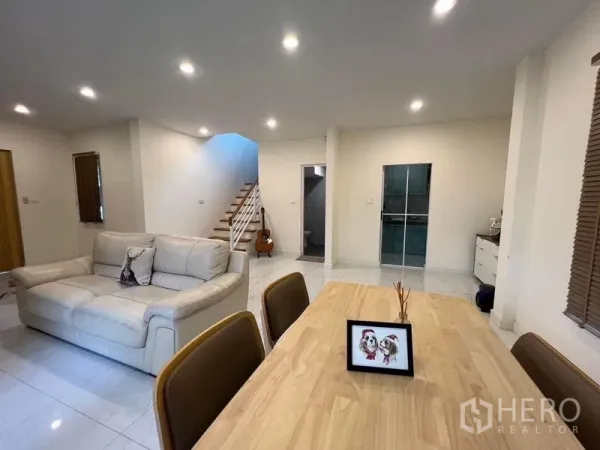 独立式住宅 出售在Bang Kruai, Nonthaburi - 客餐厅一体空间，沙发、木餐桌，亮面地砖与楼梯。
