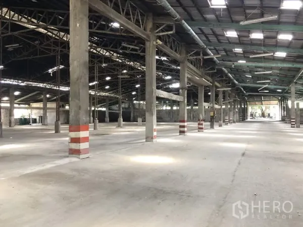 คลังสินค้า ให้เช่าในThanyaburi, Pathum Thani - ภายในโกดังขนาดใหญ่ พื้นคอนกรีต หลังคาโครงเหล็กสูง มีช่องแสง และเสาคาดแถบสีเพื่อความปลอดภัย