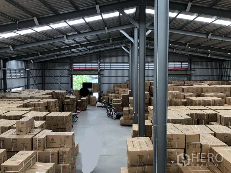 Warehouse for rent in Nonthaburi - Spacious warehouse interior with steel structure and stacks of cardboard boxes on the floor.