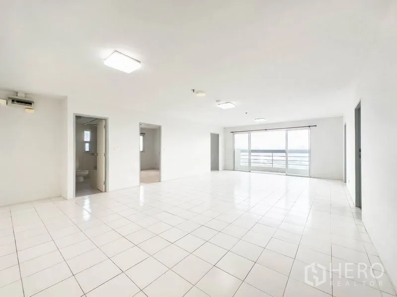 คอนโด ขายในBang Na, Bangkok - ห้องนั่งเล่นปูกระเบื้องสีขาวกว้าง เชื่อมระเบียงกระจกมองวิวเมือง.