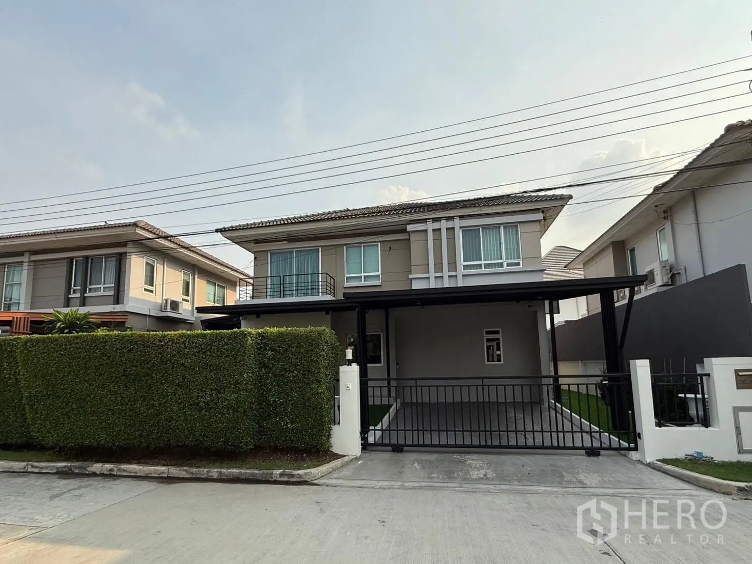 Detached House for rent in Prawet, Bangkok - Modern two-storey detached house facade with gated carport and tall hedge.