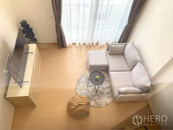 Condominium for rent in Watthana, Bangkok - Airy living room with tall windows and sofa viewed from above.