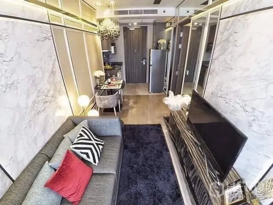 Condominium for rent or sale in Watthana, Bangkok - View from sofa to entry showing TV console, dark rug, compact kitchen, dining table, and mirrored walls.