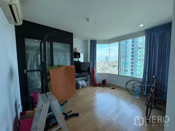 คอนโด ขายในKhlong San, Bangkok - ห้องอเนกประสงค์พื้นไม้ พร้อมอุปกรณ์ออกกำลังกายและหน้าต่างรอบมุม.