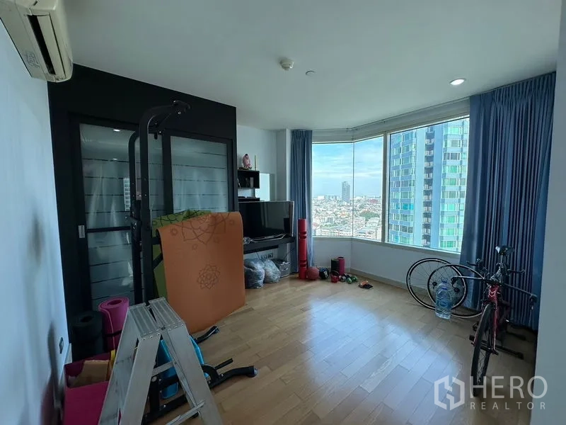 คอนโด ขายในKhlong San, Bangkok - ห้องอเนกประสงค์พื้นไม้ พร้อมอุปกรณ์ออกกำลังกายและหน้าต่างรอบมุม.