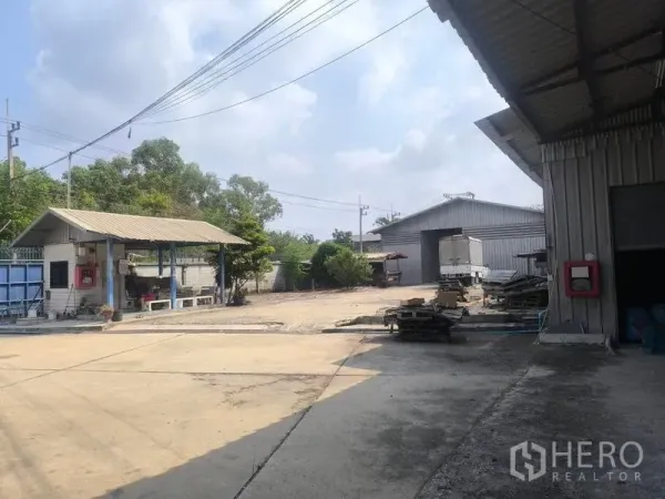 Warehouse for rent in Lat Lum Kaeo, Pathum Thani - Entrance area with small gatehouse, separate warehouse buildings and open storage space.