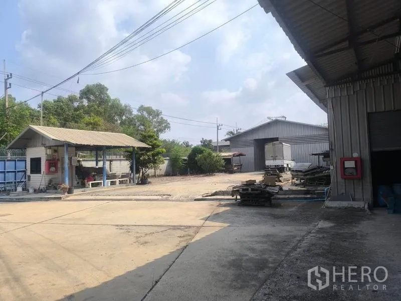 Warehouse for rent in Lat Lum Kaeo, Pathum Thani - Entrance area with small gatehouse, separate warehouse buildings and open storage space.
