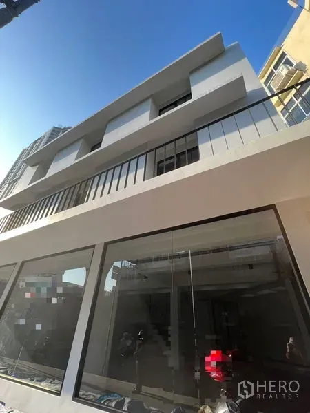 อาคารพาณิชย์ ให้เช่าในKhlong Toei, Bangkok - มุมมองเงยของอาคารพาณิชย์รีโนเวทใหม่หลายชั้น พร้อมระเบียงและกระจกหน้ากว้างท่ามกลางท้องฟ้าใส.