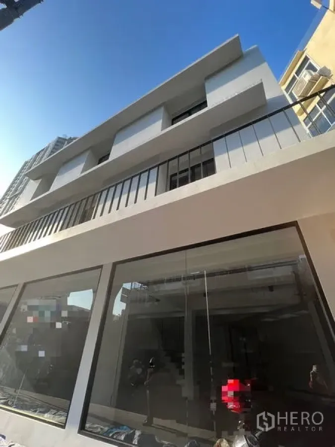 อาคารพาณิชย์ ให้เช่าในKhlong Toei, Bangkok - มุมมองเงยของอาคารพาณิชย์รีโนเวทใหม่หลายชั้น พร้อมระเบียงและกระจกหน้ากว้างท่ามกลางท้องฟ้าใส.