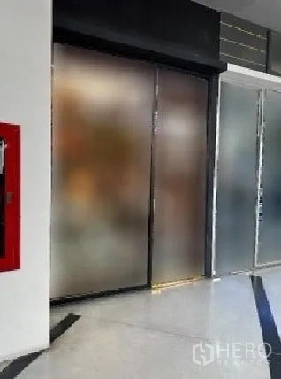 พื้นที่ขายปลีก ให้เช่าในKhlong Toei, Bangkok - ยูนิตค้าปลีกในอาคาร ประตูกระจกฝ้าแบบเลื่อน พื้นกระเบื้องเงา และตู้ดับเพลิงสีแดงในโถงทางเดิน