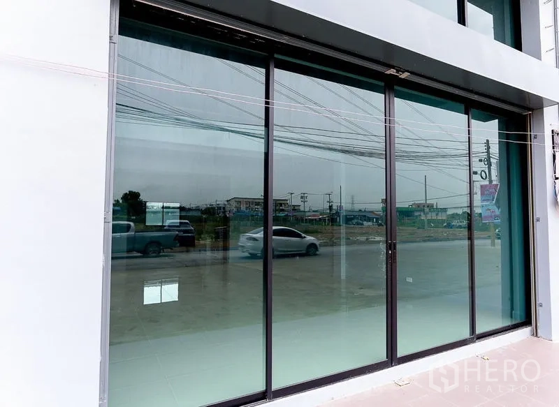 Shophouse for sale in Lam Luk Ka, Pathum Thani - Wide sliding glass storefront facing the main road.
