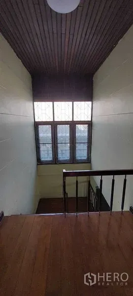 Townhouse for sale - Double-height stairwell featuring a tall multi-pane window and wooden handrail.