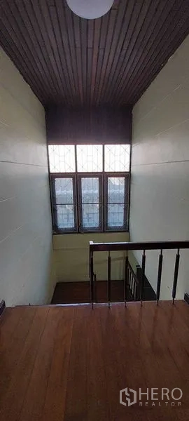 Townhouse for sale - Double-height stairwell featuring a tall multi-pane window and wooden handrail.