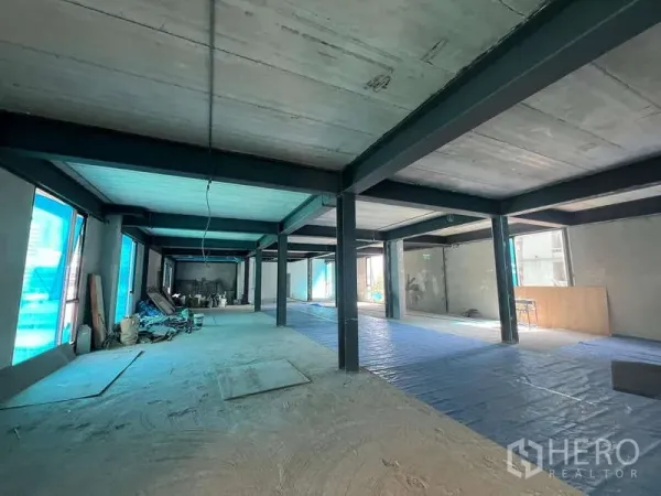 零售空间 出租在Pathum Wan, Bangkok - 大型零售单元装修进行中，一侧堆放材料，立面窗户明亮。