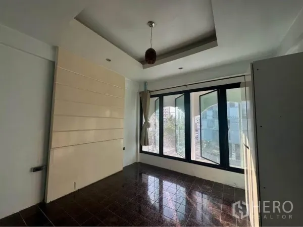 Shophouse for rent in Bang Rak, Bangkok - Upper-floor room with tray ceiling, large bay windows, and dark tile flooring.