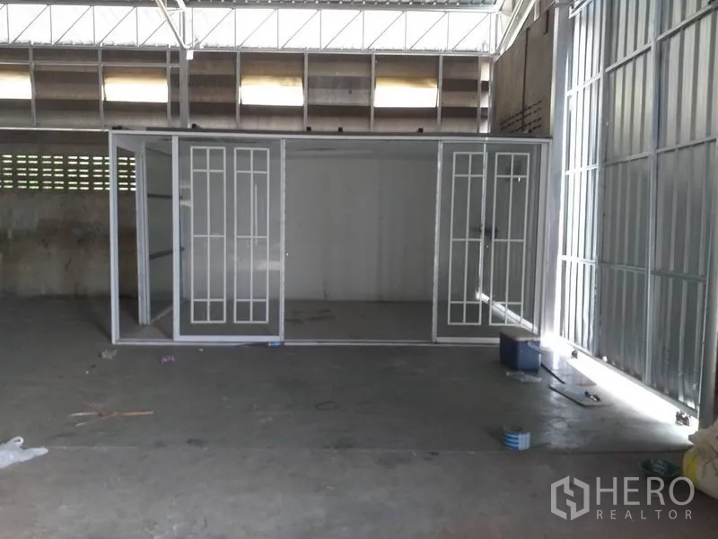 Warehouse for rent in Pak Kret, Nonthaburi - Glass-partitioned internal office room inside the warehouse beneath skylight panels.