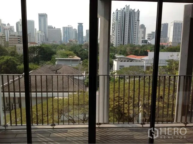 Condominium for rent or sale in Watthana, Bangkok - Balcony with railings overlooking green treetops and the Bangkok skyline