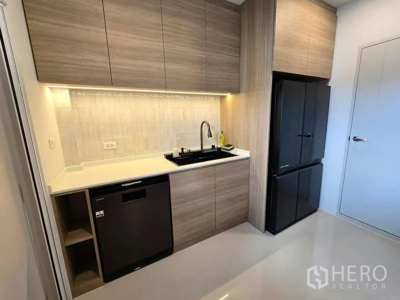 Detached House for rent in Bang Phli, Samut Prakan - Modern pantry kitchen with wood cabinetry, black fridge and dishwasher.