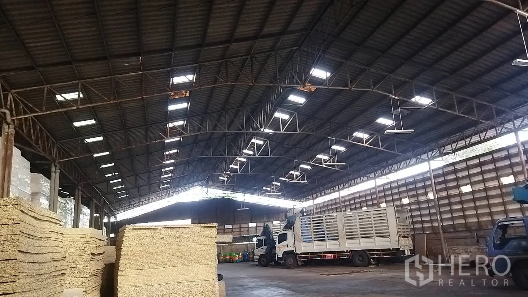 Warehouse for rent in Bang Khun Thian, Bangkok - Wide interior angle highlighting clear-span structure, natural light panels, and loading trucks.