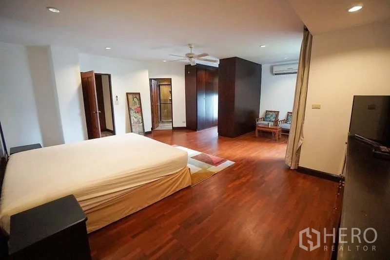 อพาร์ทเมนท์ ให้เช่าในWatthana, Bangkok - ห้องนอนใหญ่พื้นไม้พร้อมมุมนั่งเล่นและตู้เสื้อผ้า