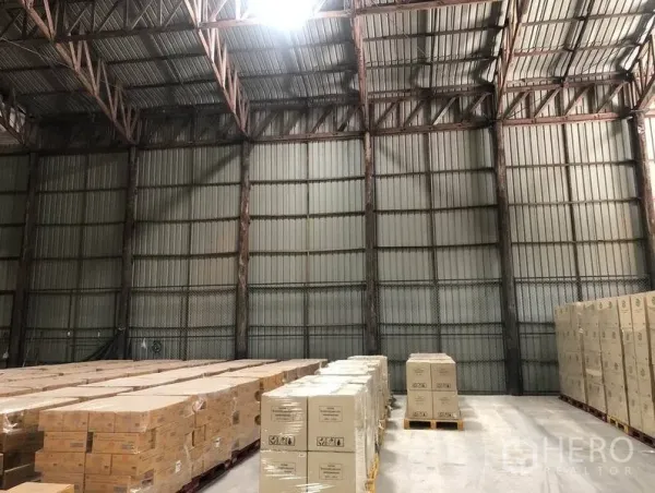 货栈 出租在Pak Kret, Nonthaburi - 仓库内部挑高钢结构屋顶，混凝土地面，整齐的托盘货物。