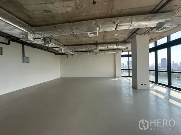 Office Space for rent in Watthana, Bangkok - Large office interior with polished floors, white walls, exposed HVAC ducts and corner windows framing city views.