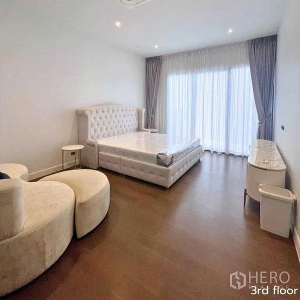 Detached House for rent in Bang Kapi, Bangkok - Master bedroom with tufted bed, wood floors and balcony-height curtains.