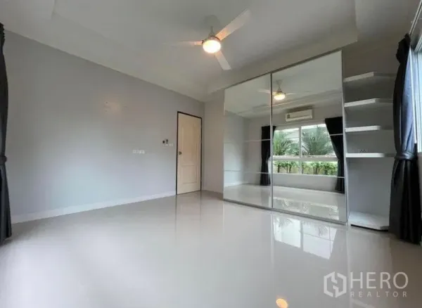 独立式住宅 出售在Bang Phli, Samut Prakan - 宽敞卧室，镜面衣柜、吊扇与大窗景观花园。