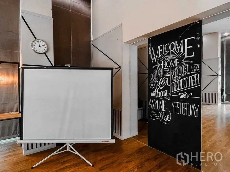 Office Space for rent in Lak Si, Bangkok - Presentation zone with portable projector screen, wall clock and chalkboard welcome sign in a modern office interior.