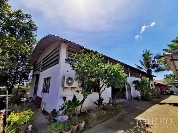 คลังสินค้า ขายในPathum Thani - ด้านนอกโกดังหลังคาโค้ง ผนังสีขาว มีต้นไม้และทางเข้ารถ ใต้ท้องฟ้าสดใสในคลองหลวง