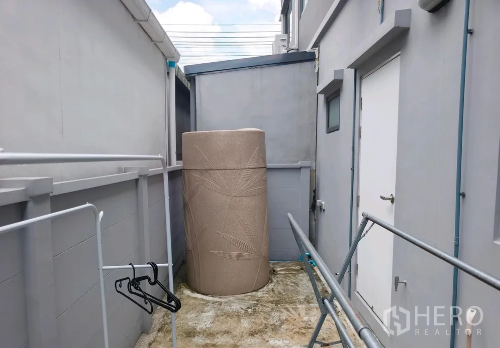 Townhouse for rent in Bang Phli, Samut Prakan - Side yard angle showing a large water storage tank and railings.