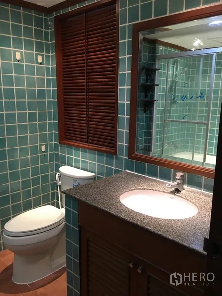 Condominium for rent in Pathum Wan, Bangkok - Bathroom with green square tiles, vanity, and toilet.