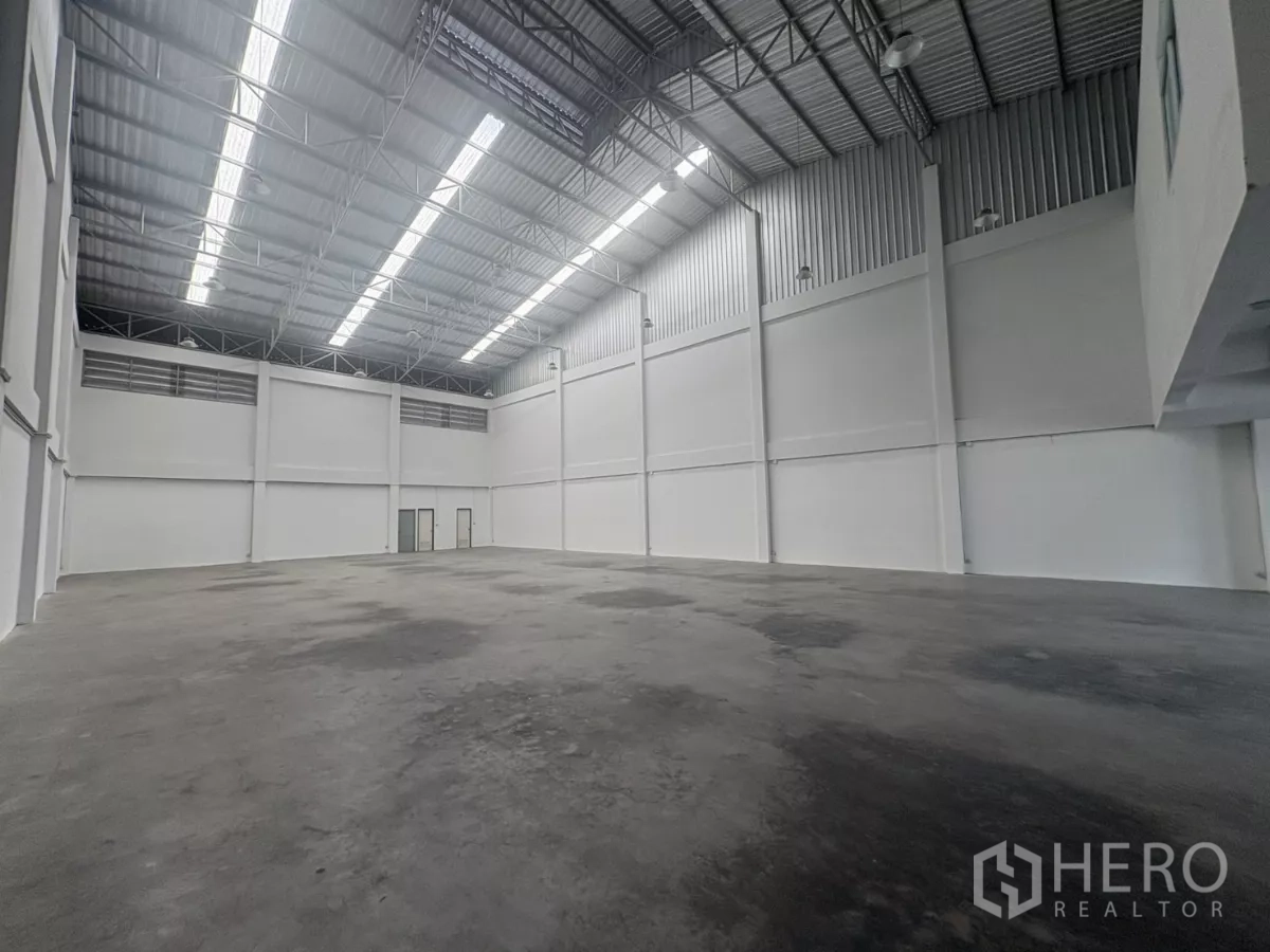 Factory for rent in Phra Samut Chedi, Samut Prakan - Clear-span production floor with polished concrete and skylight strips along the roof.