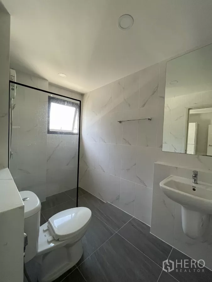 Detached House for rent in Bang Phli, Samut Prakan - Bathroom with glass partition, gray floors and white marble-look walls.