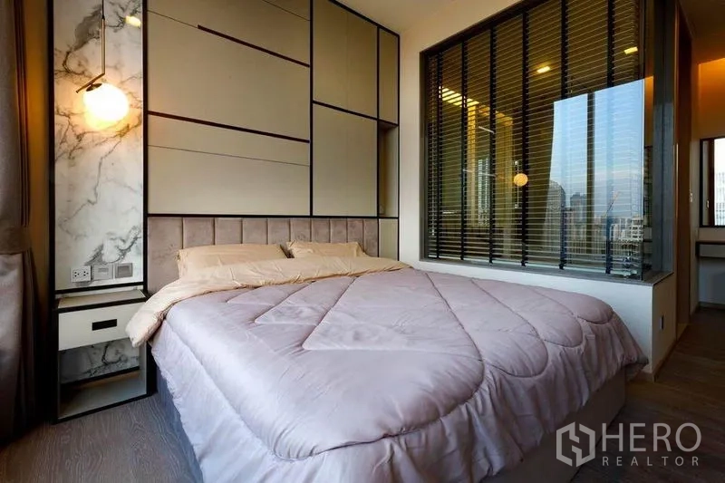 Condominium for rent or sale in Watthana, Bangkok - Cozy bedroom with feature wall, bedside light and window to city views in Watthana.