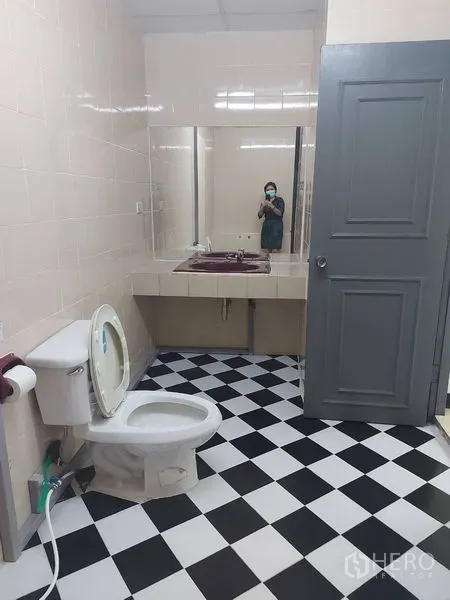 办公空间 出租在Pathum Wan, Bangkok - 黑白棋盘格地砖的卫生间，马桶与带大镜面的洗手台。