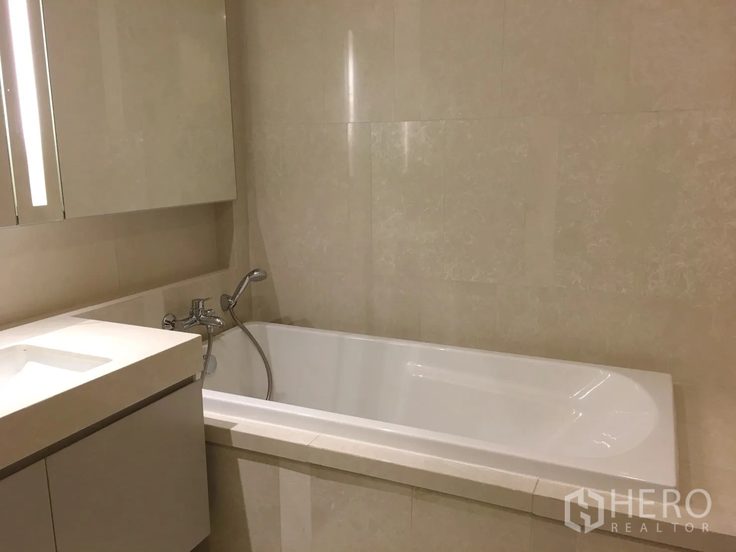 คอนโด ให้เช่าในWatthana, Bangkok - ห้องน้ำตกแต่งหินสีเบจพร้อมอ่างอาบน้ำแบบบิลท์อินและฝักบัวสายอ่อน