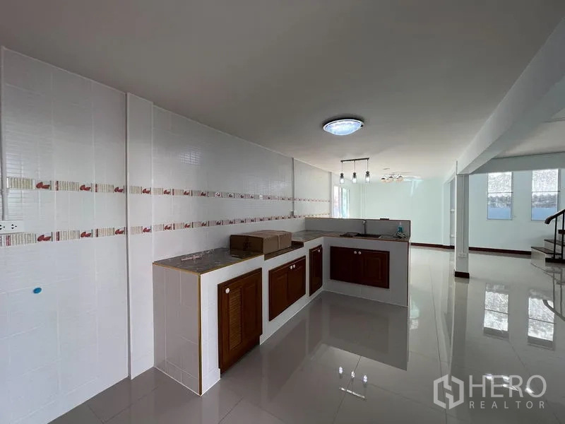 บ้าน ให้เช่าในKhlong Toei, Bangkok - ครัวรูปตัวแอล ผนังกระเบื้อง ตู้บานไม้ และเลย์เอาต์แบบโอเพนแปลน