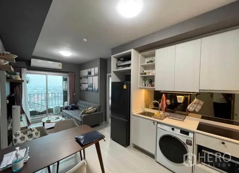 Condominium for sale in Bang Sue, Bangkok - Open kitchen and dining flowing to a balcony with skyline and river view.